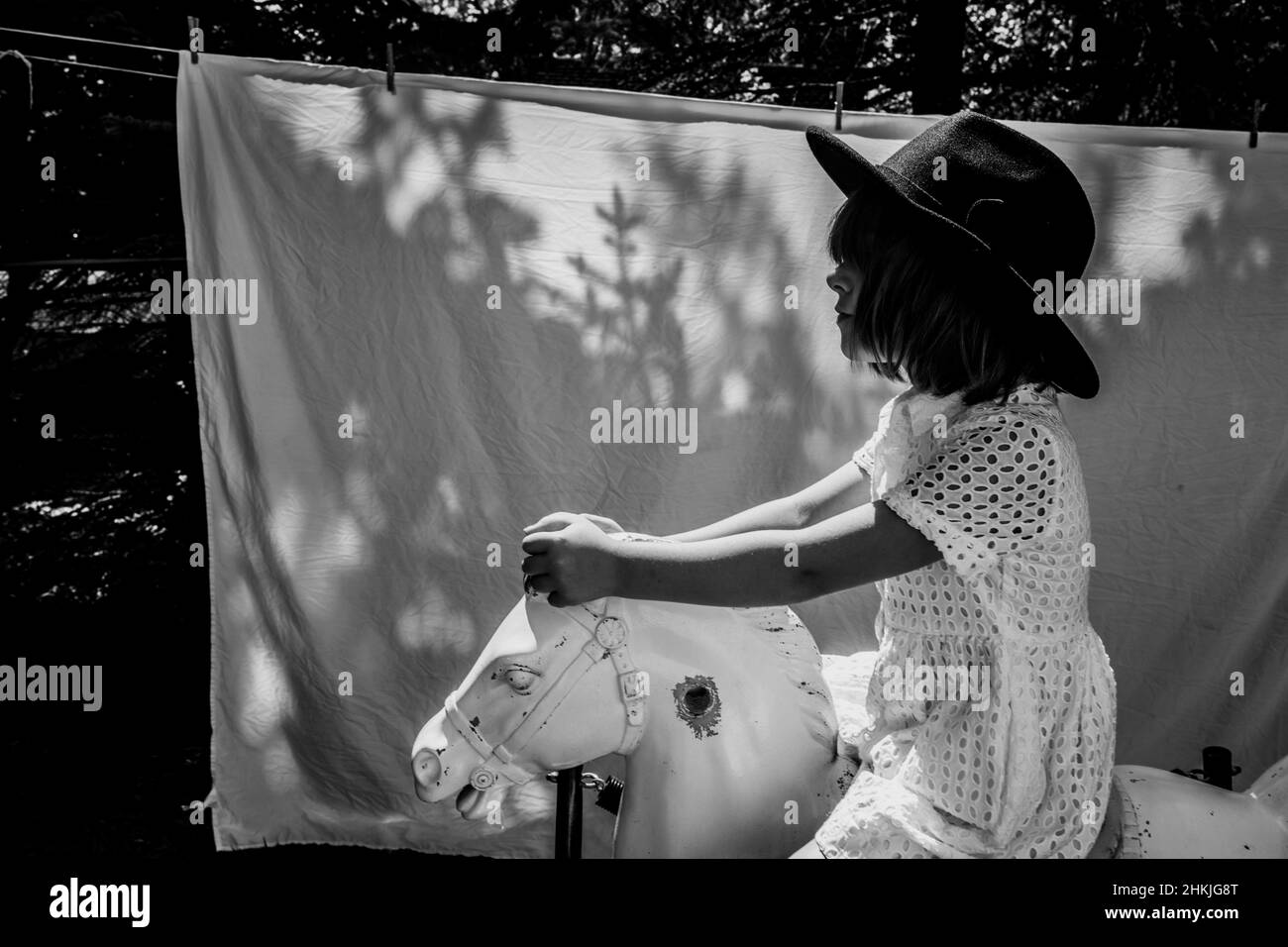 Girl riding on toy horse outside Stock Photo