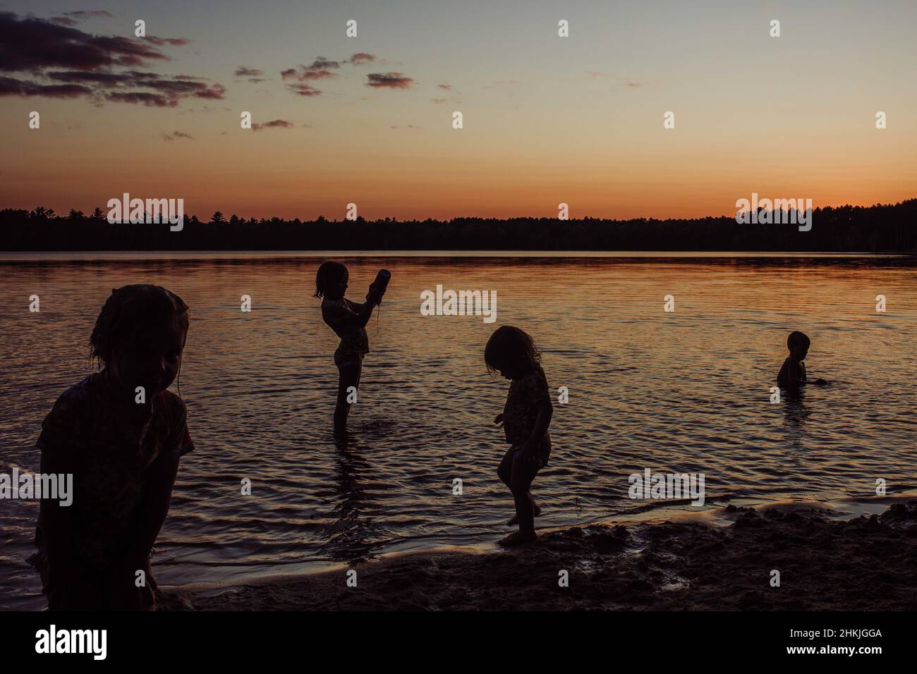 Children playing in water at sunset sunrise Stock Photo - Alamy