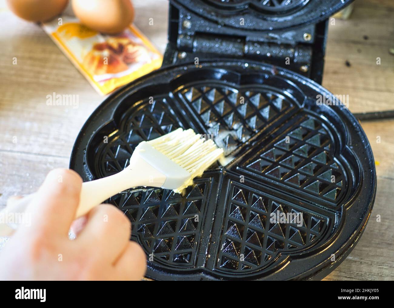 Photo of a person greasing a waffle iron pan Stock Photo Alamy