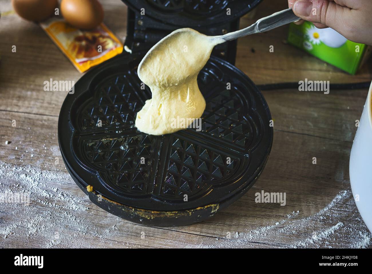Photo of a person putting waffle batter in a waffle iron pan Stock