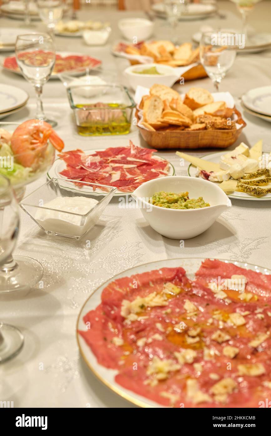 Mesa preparada con un aperitivo de jamón ibérico, guacamole, carpaccio, anchoas y otras delicias para una celebración. Stock Photo