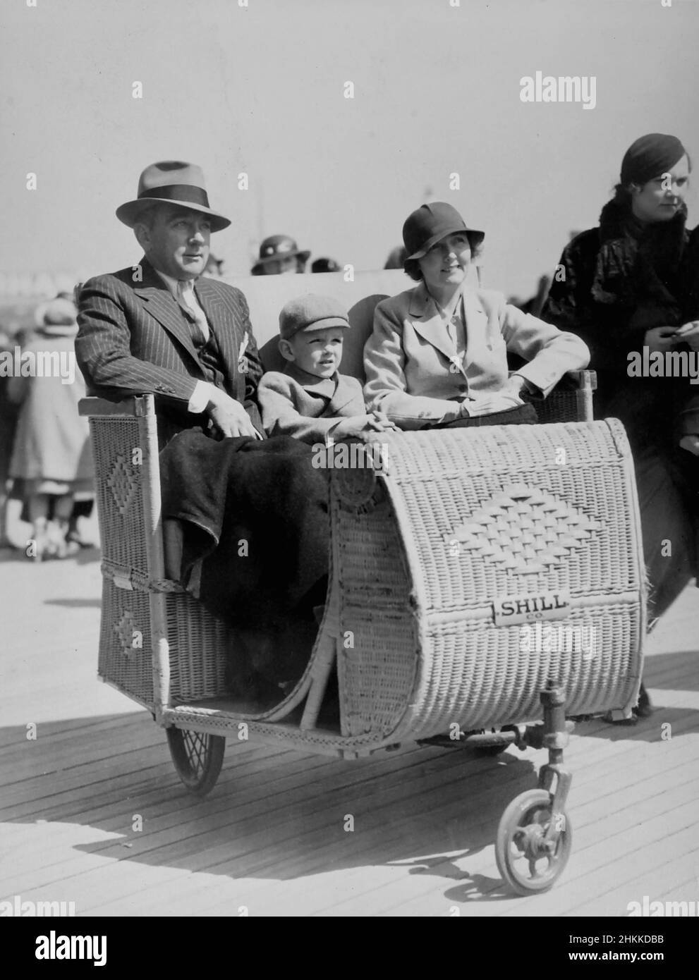 A family is shown in a Shill Co. wicker rolling car on the Atlantic City boardwalk, ca. 1935. Stock Photo
