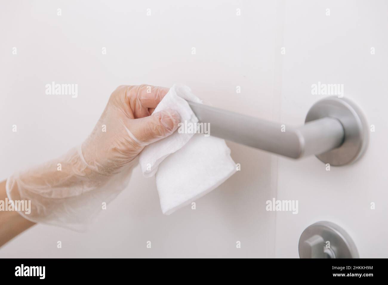 Cleaning door handles with wet wipe and white gloves. Woman hand using ...