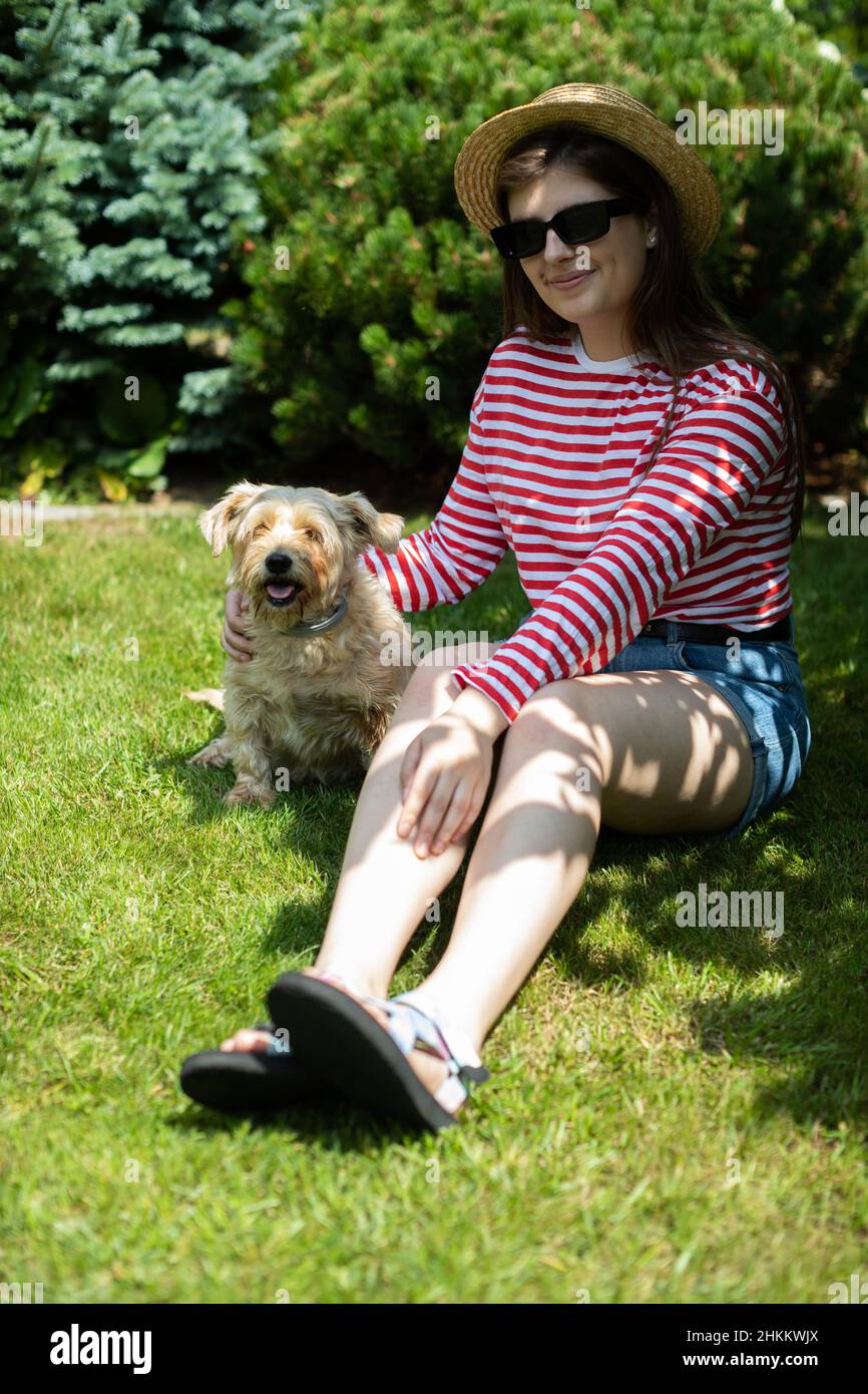 A girl sits on the grass in the shade with her dog Stock Photo - Alamy