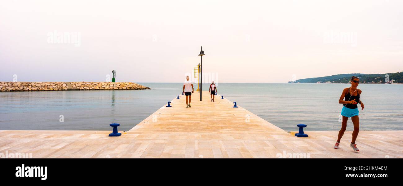 early morning sport - people train running on pier of Rodi Garganico in Puglia Stock Photo