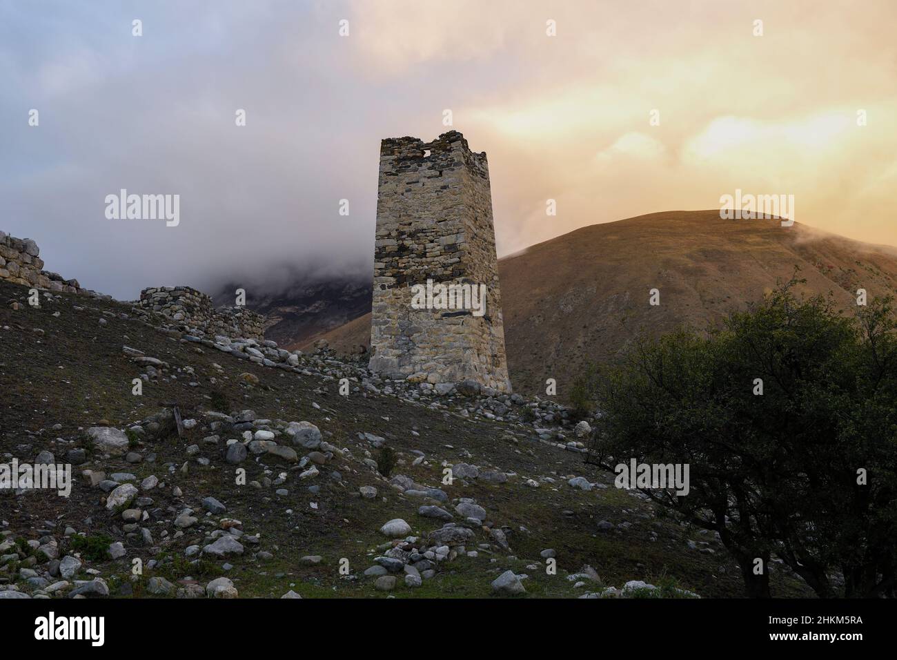 A old Ossetian battle tower against the background of sunset in foggy mountains. Verhniy Fiagdon. Northern Ossetia, Russia Stock Photo