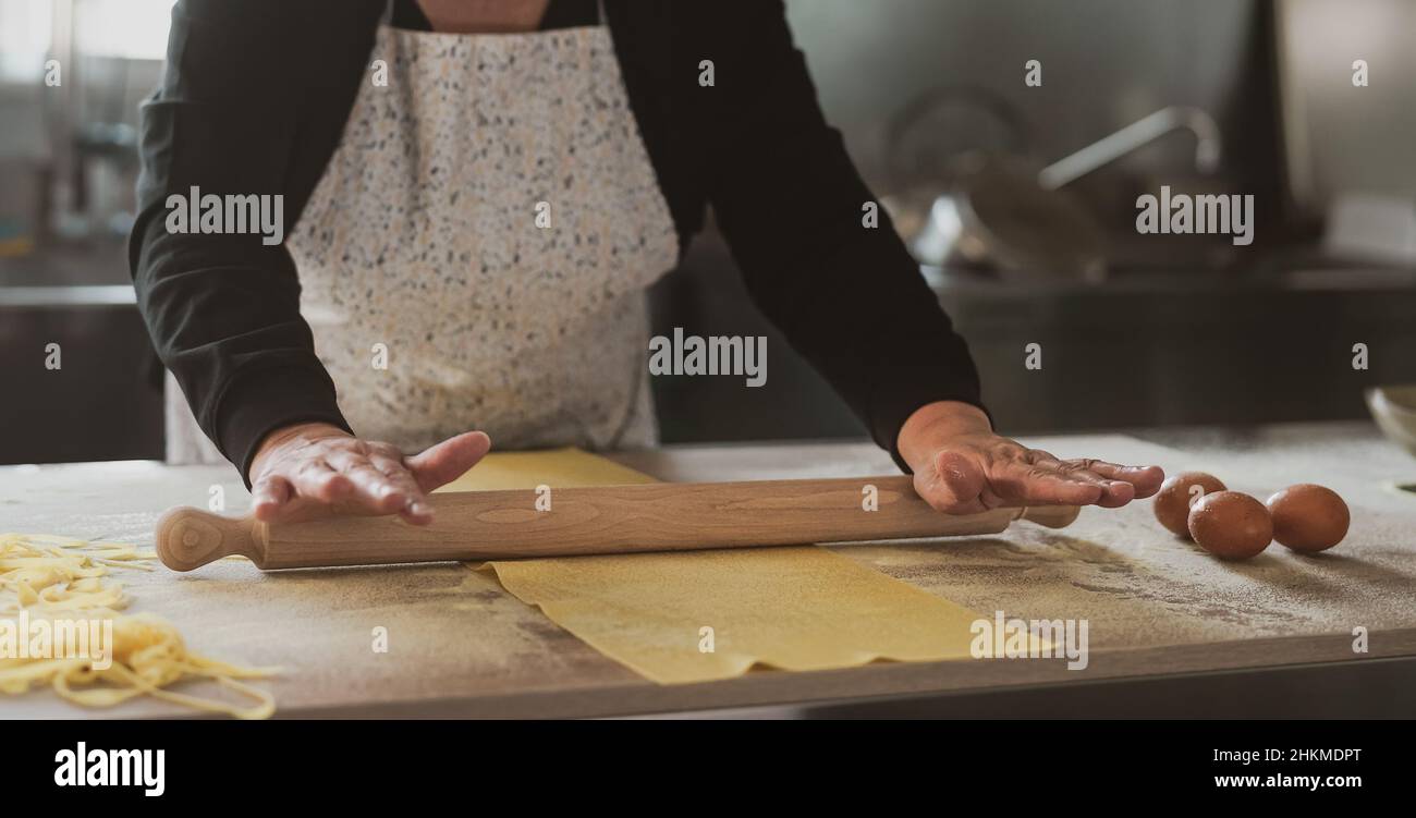 Close up female hands roll the dough preparing fresh homemade pasta Stock Photo