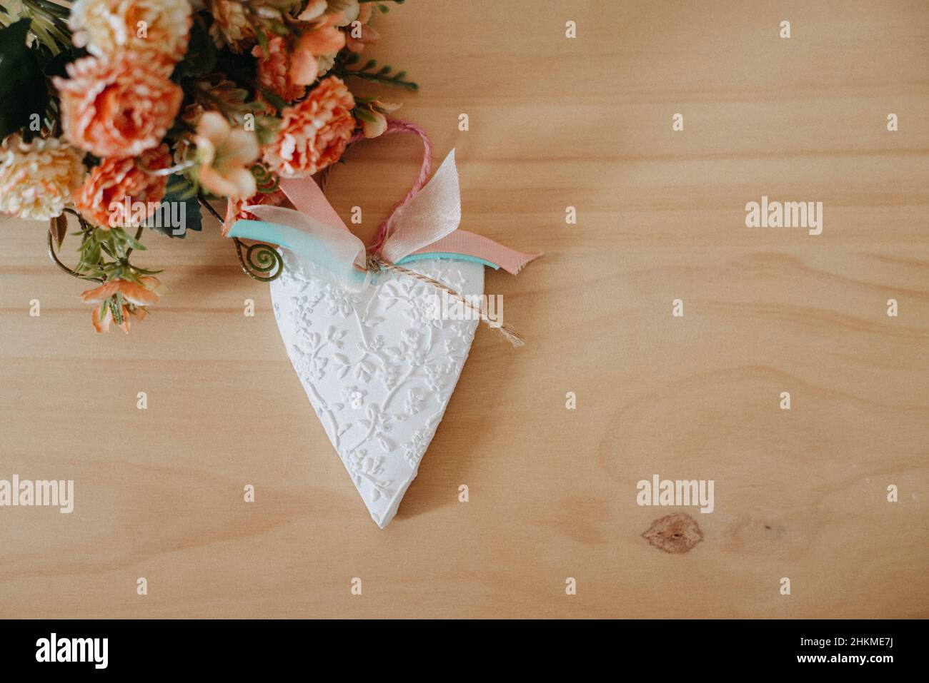 wooden table with a bouquet of flowers and a white heart Stock Photo