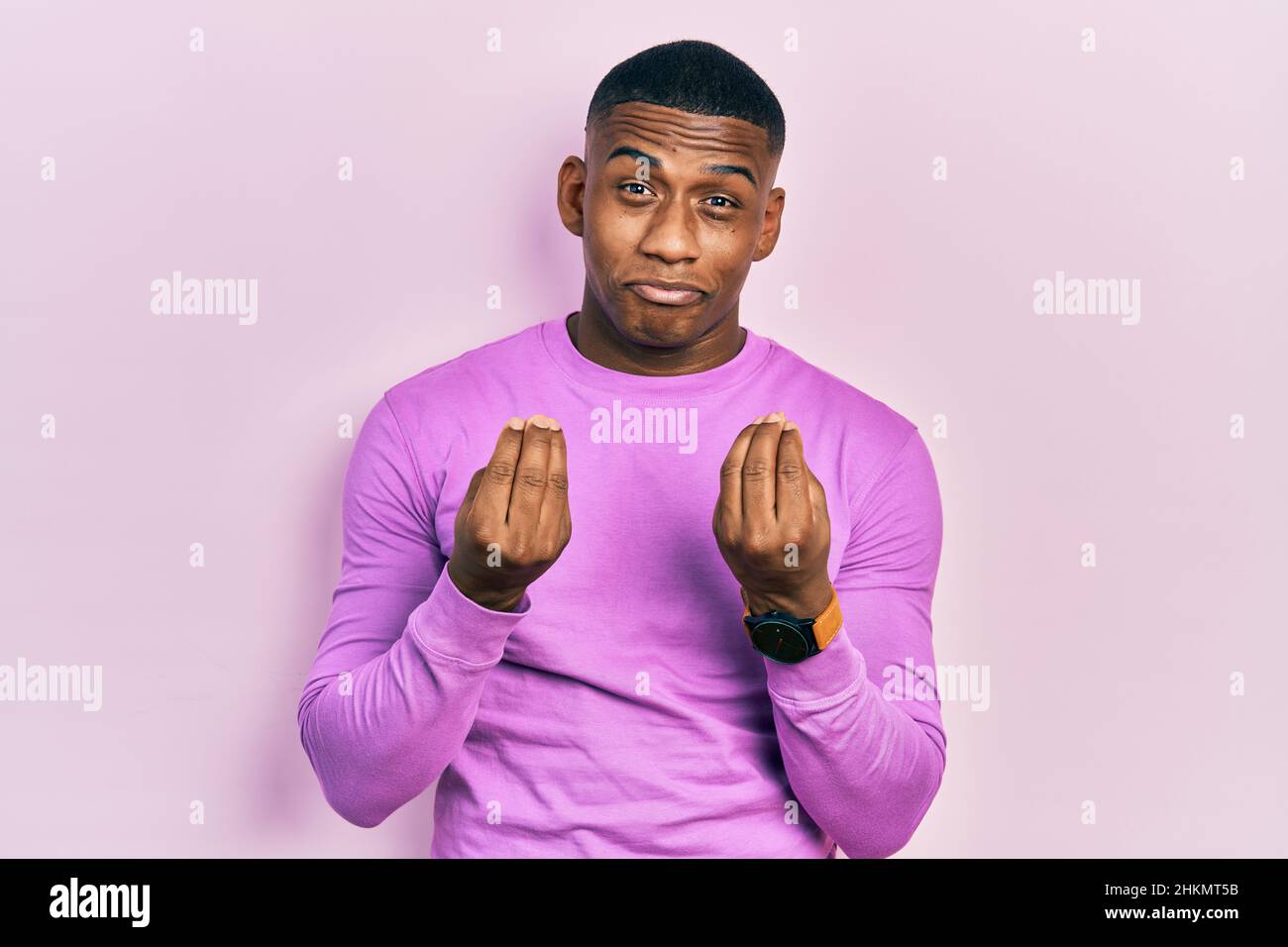 Young black man wearing casual pink sweater doing money gesture with hands,  asking for salary payment, millionaire business Stock Photo - Alamy