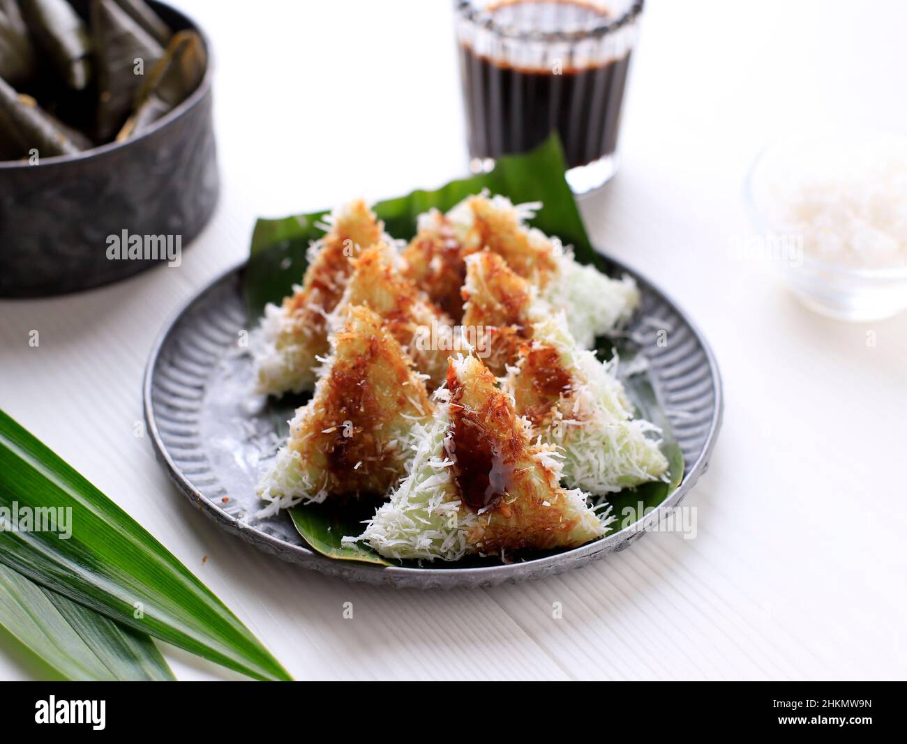 Lupis, Indonesian Traditional Snack Made From Sticky Rice, Wrapped with Banana Leaf, Shape Triangle  Served with Liquid Palm Sugar and Grated  Coconut Stock Photo