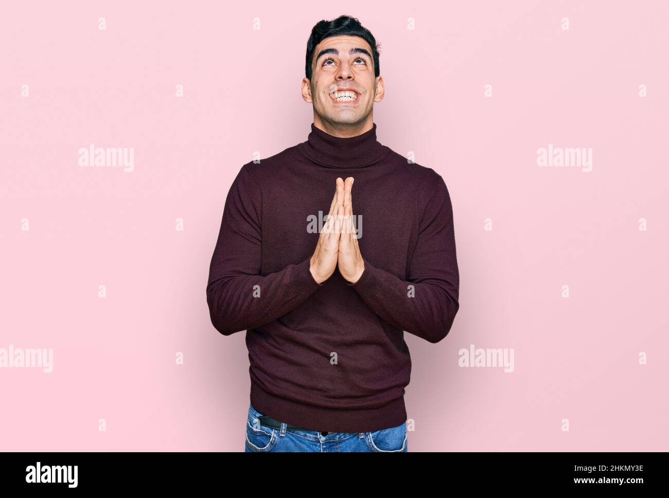 Handsome hispanic man wearing casual turtleneck sweater begging and praying with hands together with hope expression on face very emotional and worrie Stock Photo