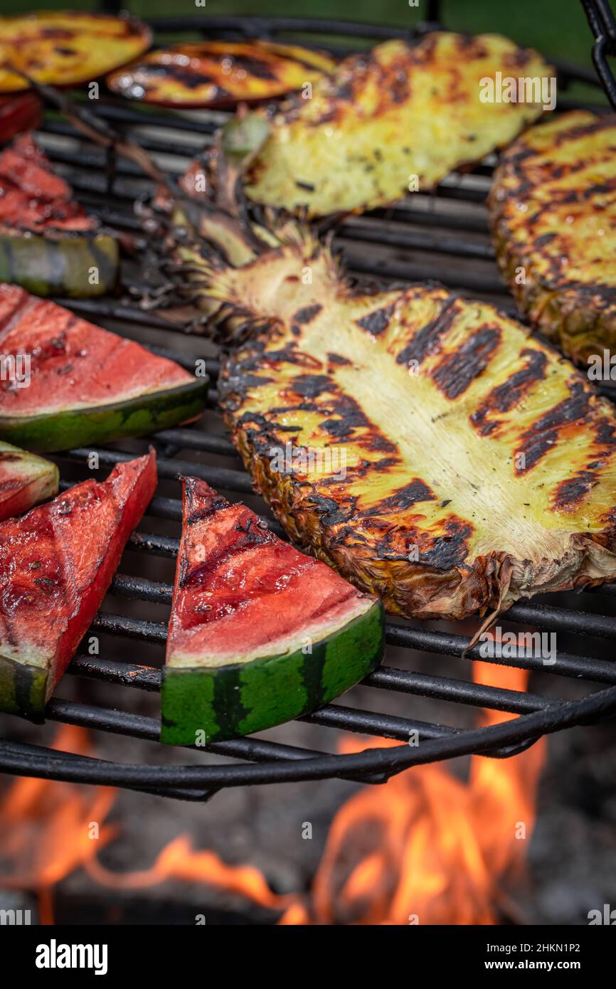 Hot roasted watermelon and pineapple on bonfire with flames. Grilled ...