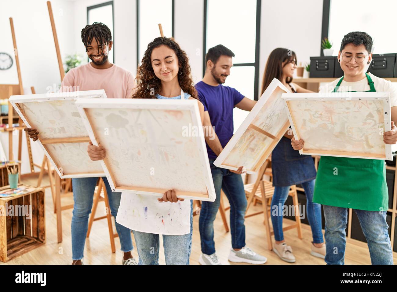 Group of young paint students smiling happy holding canvas standing at