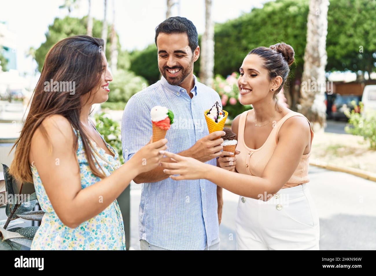 Three hispanic friends smiling happy eating ice cream at the city. Stock Photo