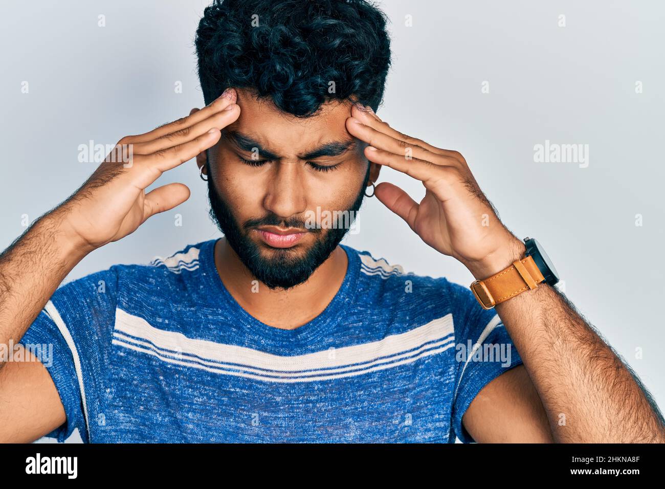 Arab man with beard wearing casual striped t shirt suffering from ...