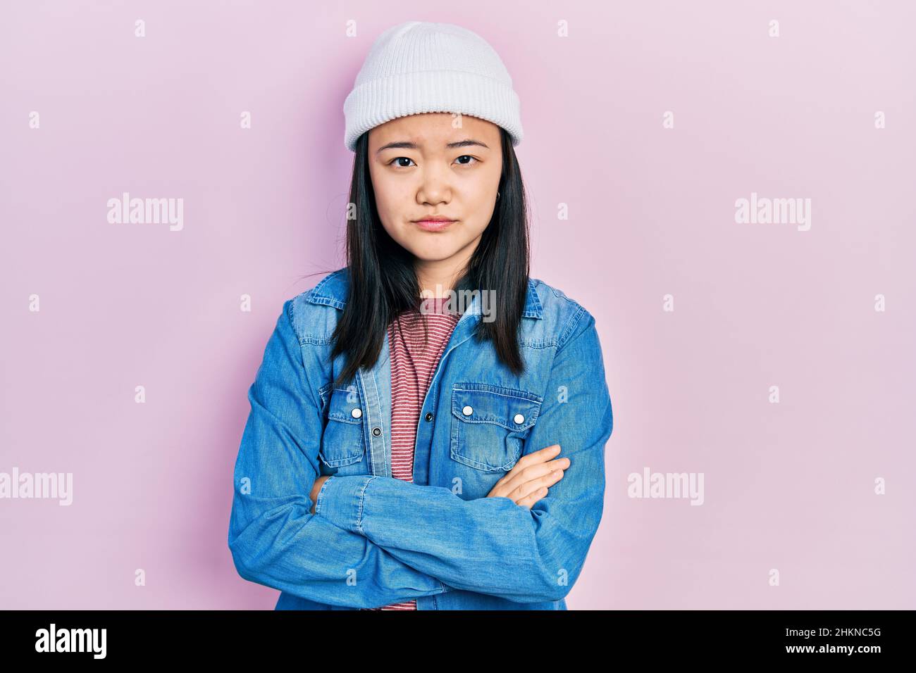 Young chinese girl wearing cute wool cap skeptic and nervous, disapproving expression on face with crossed arms. negative person. Stock Photo