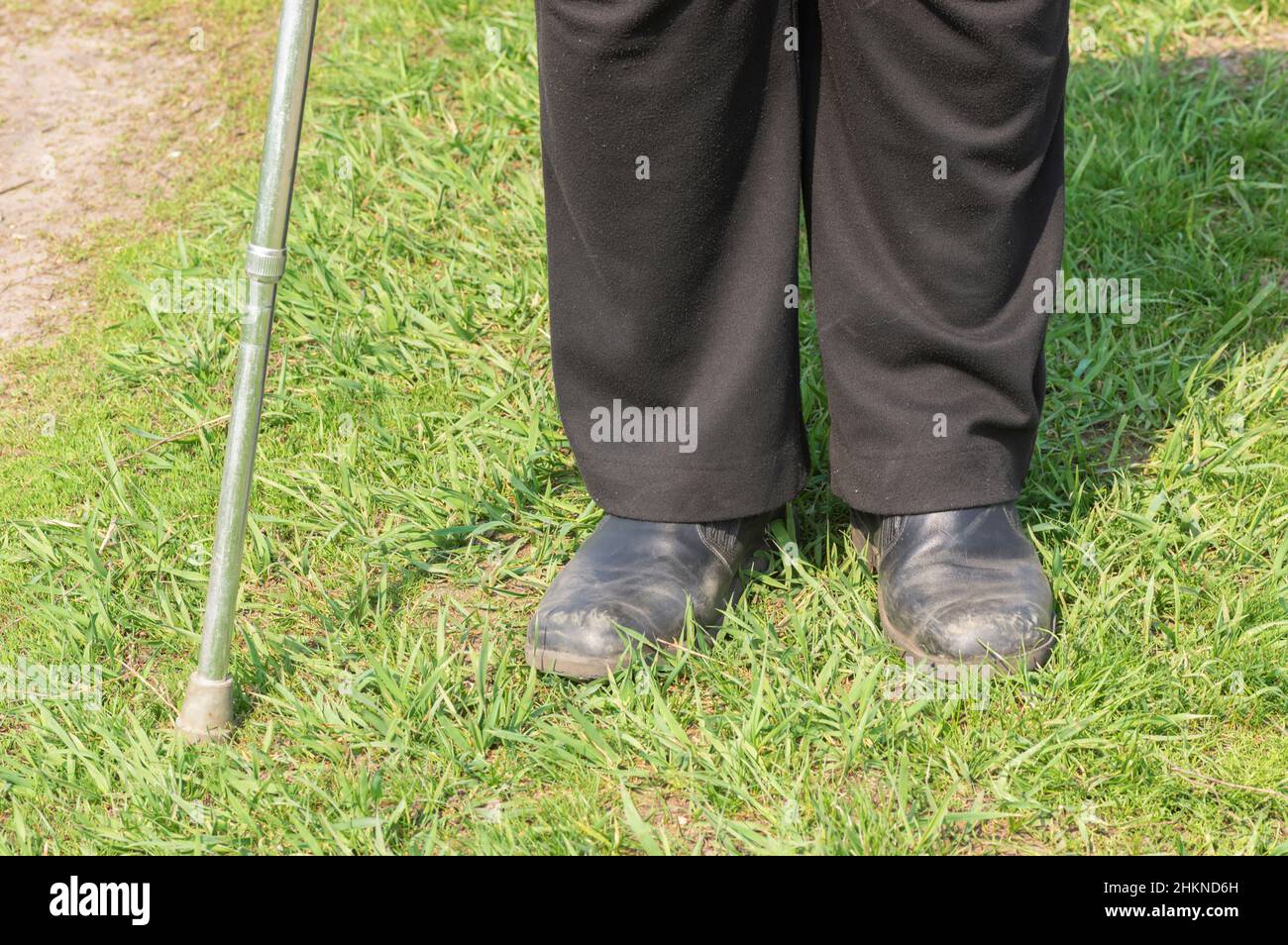 Ukrainian man with walking stick wearing old scratched shoes, and ordinary black pants standing beside path and ready to walk at spring season Stock Photo