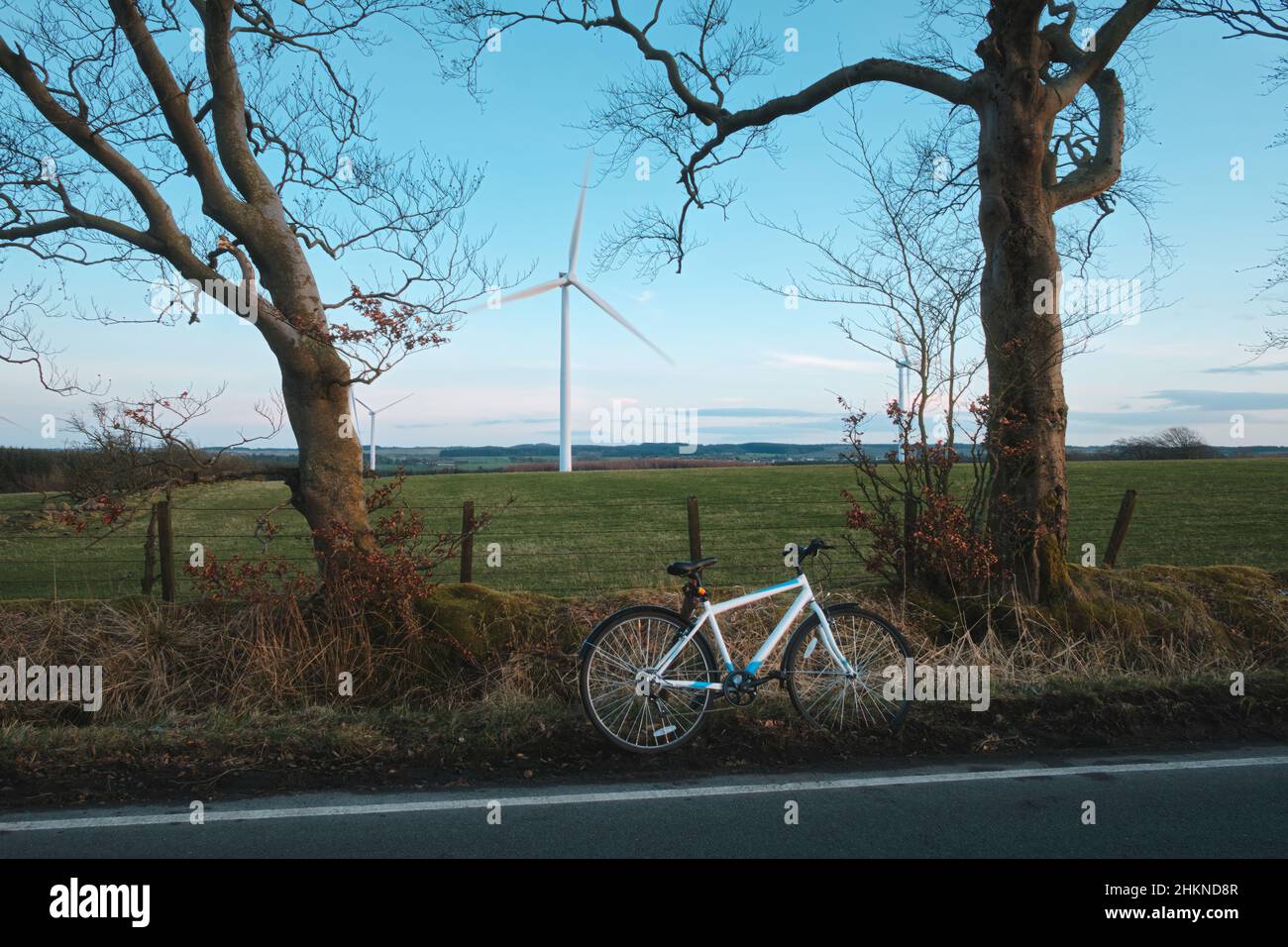 Bicycle on the side of a countryside road. Windmills in the background. West Lothian, Scotland, United Kingdom Stock Photo