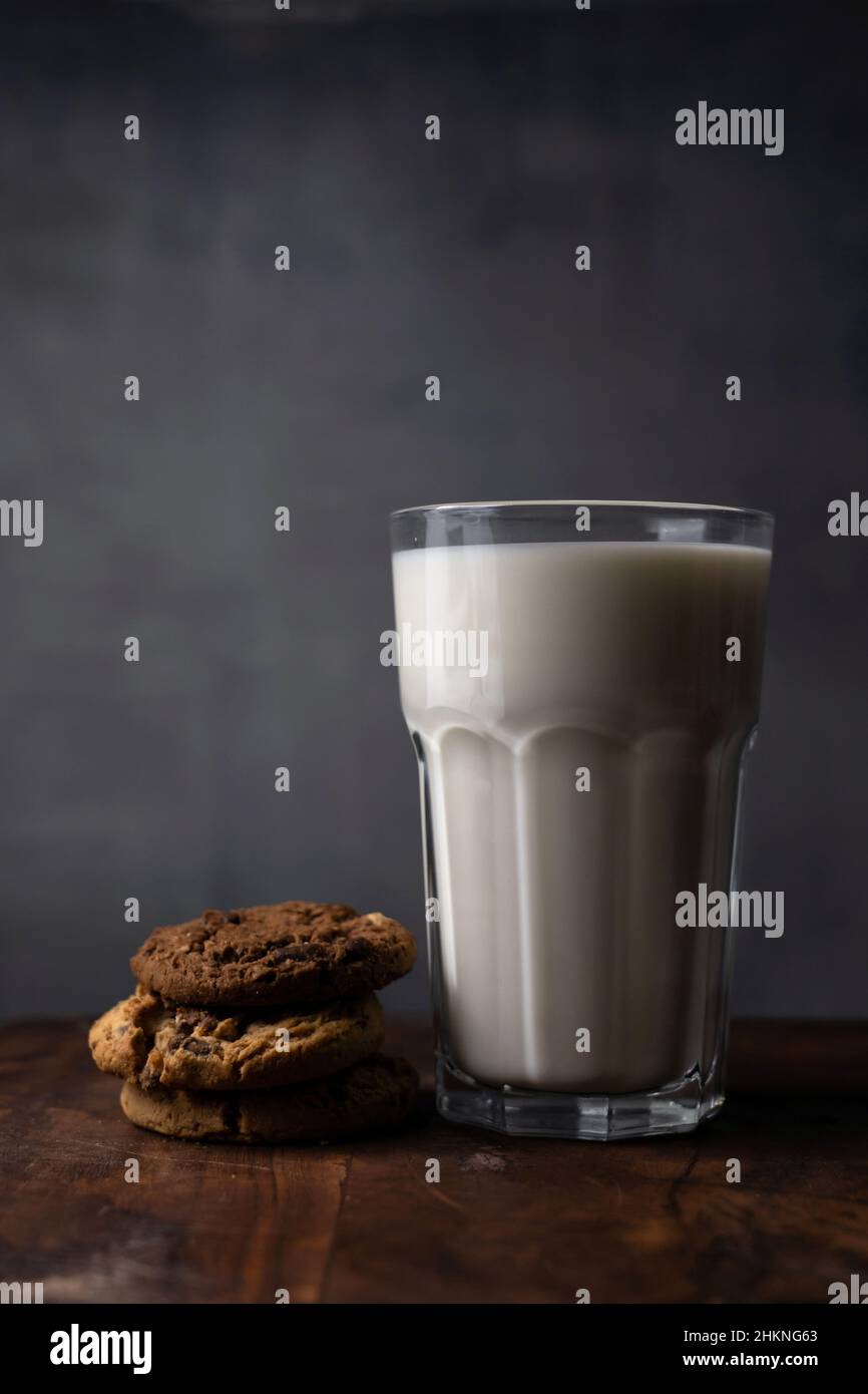 A glass of milk with chocolate chips cookies on a rustic table Stock Photo