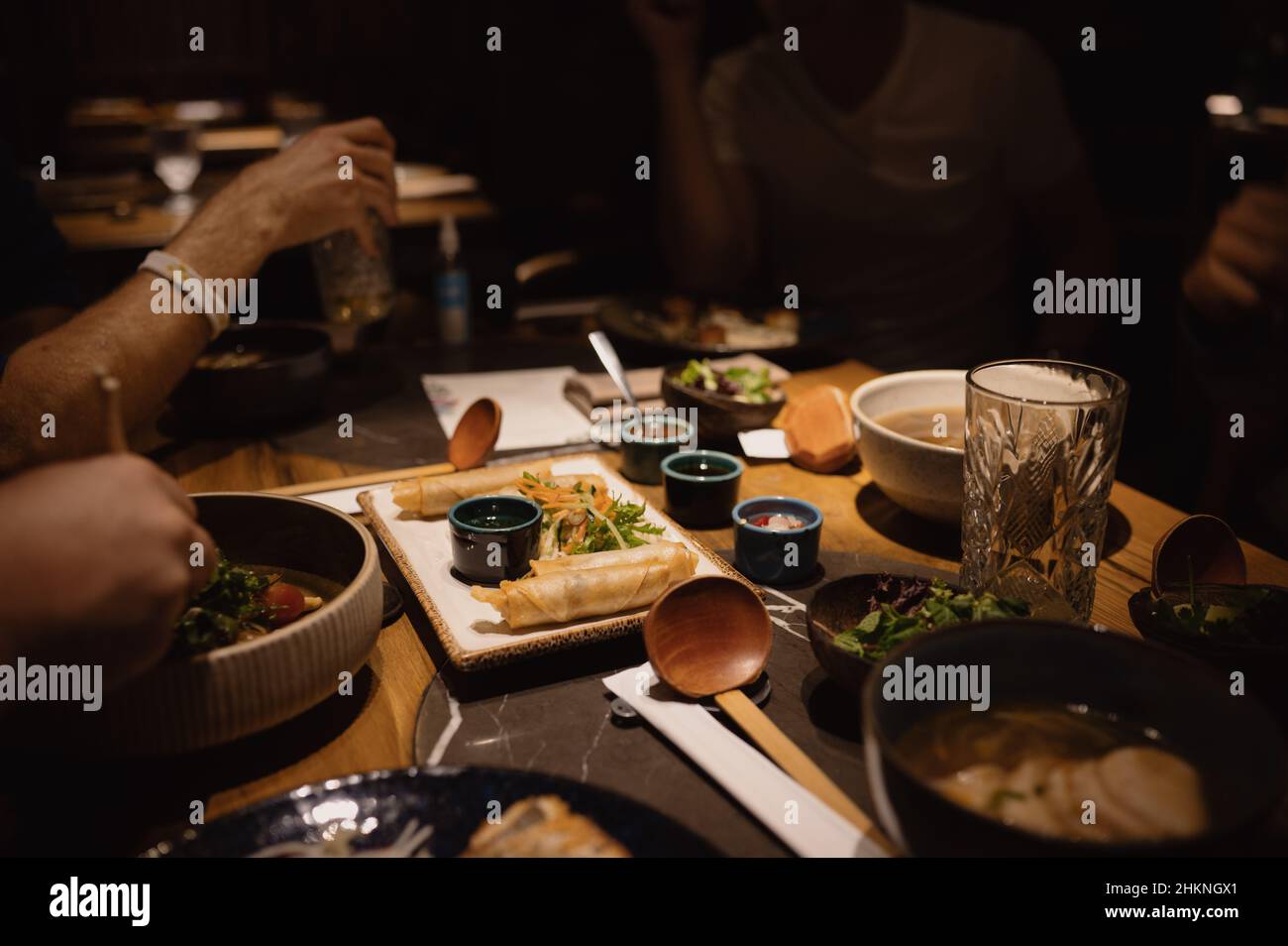 Friends eat a delicious Asian meal seated around a table in a nice restaurant. Stock Photo