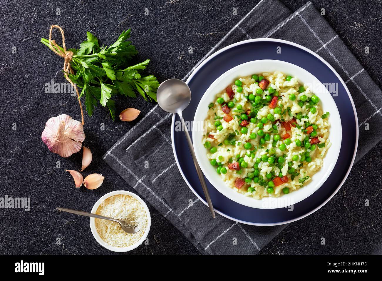 Risi e Bisi, Venetian Risotto with Spring Peas and chunks of ham in a bowl on a concrete table with ingredients, italian cuisine, horizontal view from Stock Photo