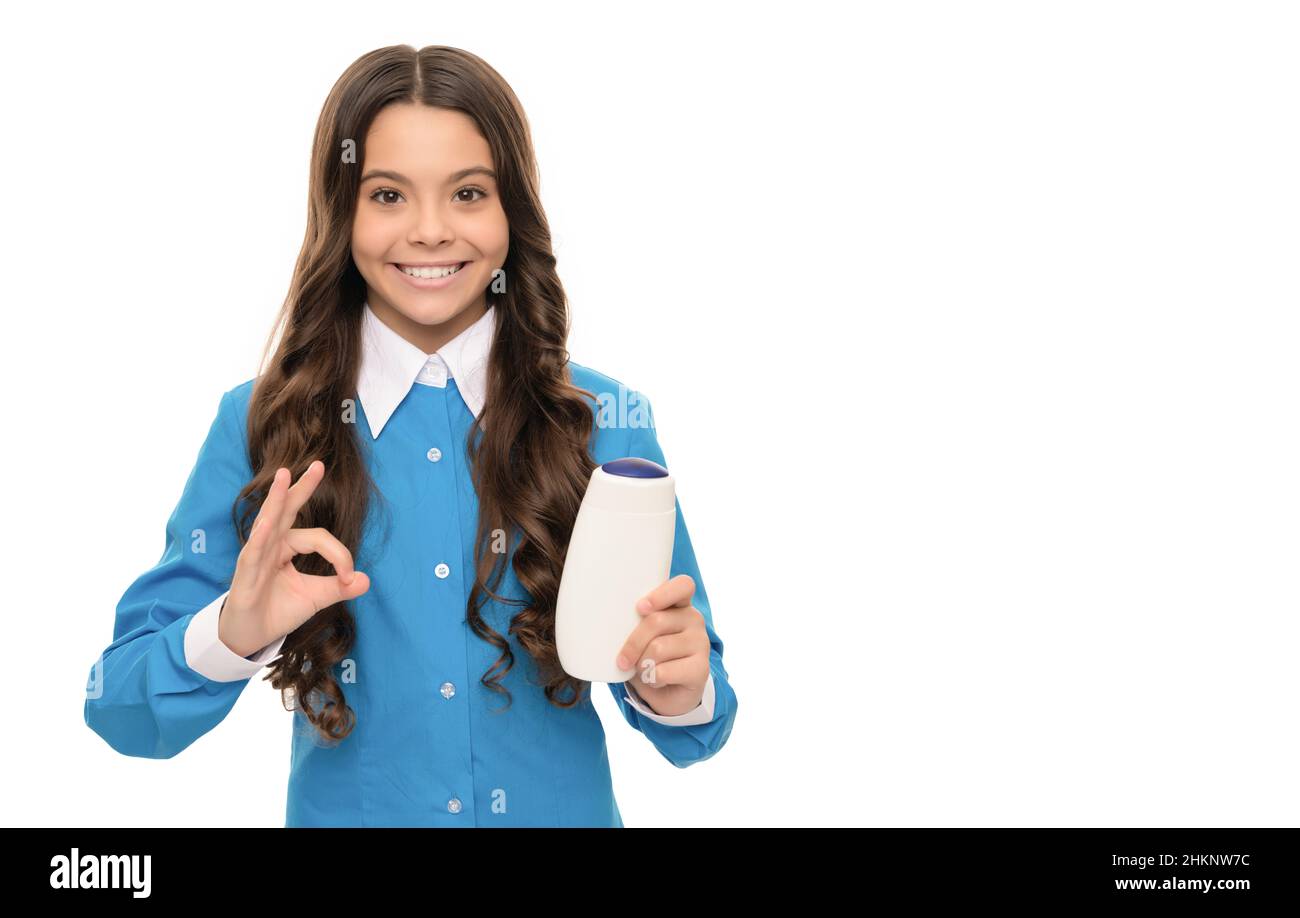 happy face of teen girl presenting shampoo isolated on white show ok gesture, keratin. Stock Photo