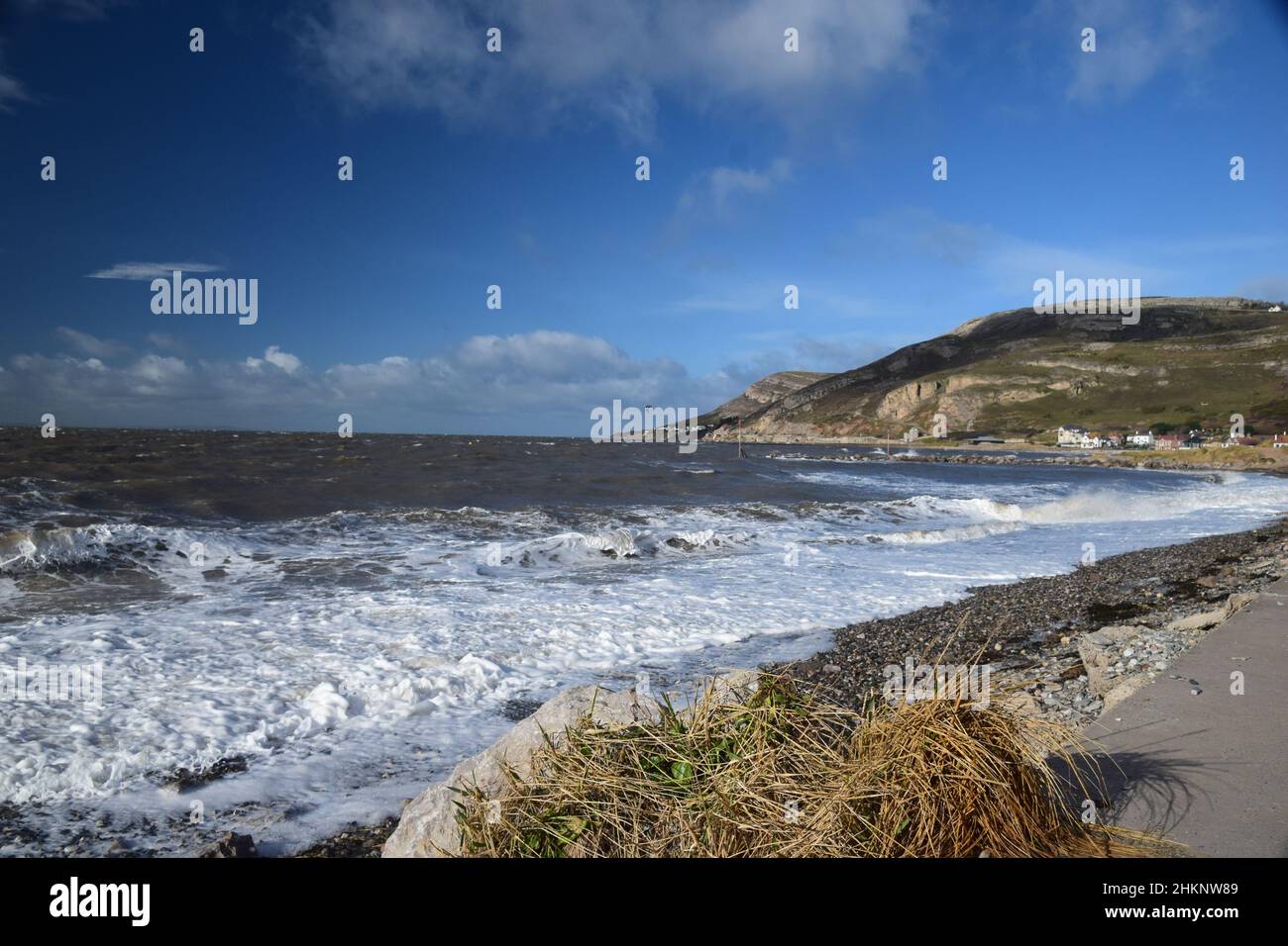 Breaking waves pound in onto a shingle beach by the Great Orme Llandudno Stock Photo