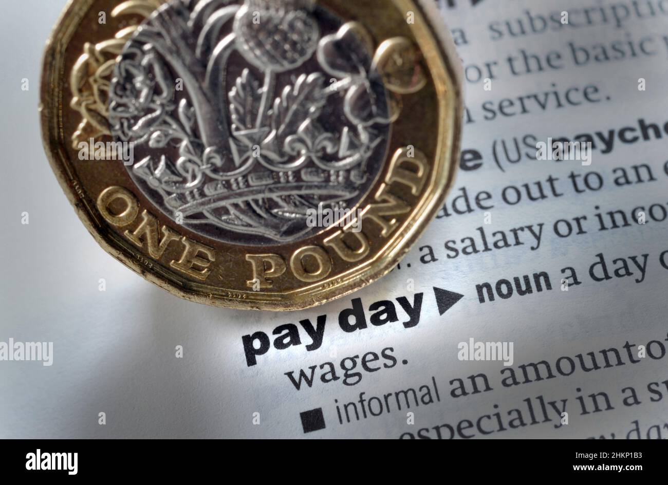 DICTIONARY DEFINITION OF WORDS PAY DAY WITH ONE POUND COIN RE INCOMES COST OF LIVING WAGES SALARY WORKERS PAY ETC UK Stock Photo