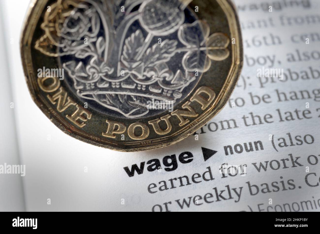 DICTIONARY DEFINITION OF WORD WAGE WITH ONE POUND COIN RE INCOMES COST OF LIVING WAGES SALARY WORKERS PAY ETC UK Stock Photo