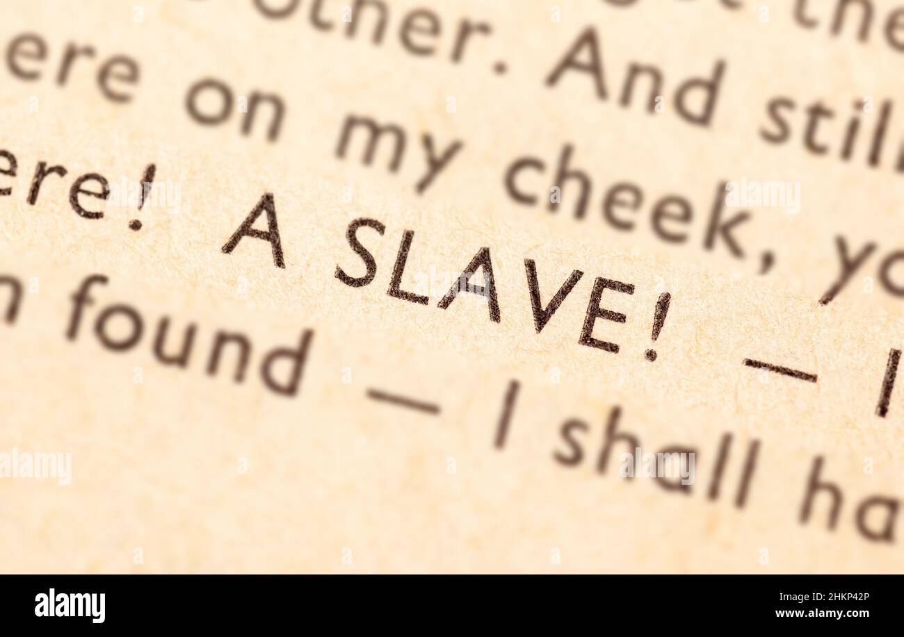 A word 'Slave' in an old yellowed book, detail, extreme closeup, macro, selective focus, shallow dof, nobody. Slavery, enslavement, exploitation abstr Stock Photo