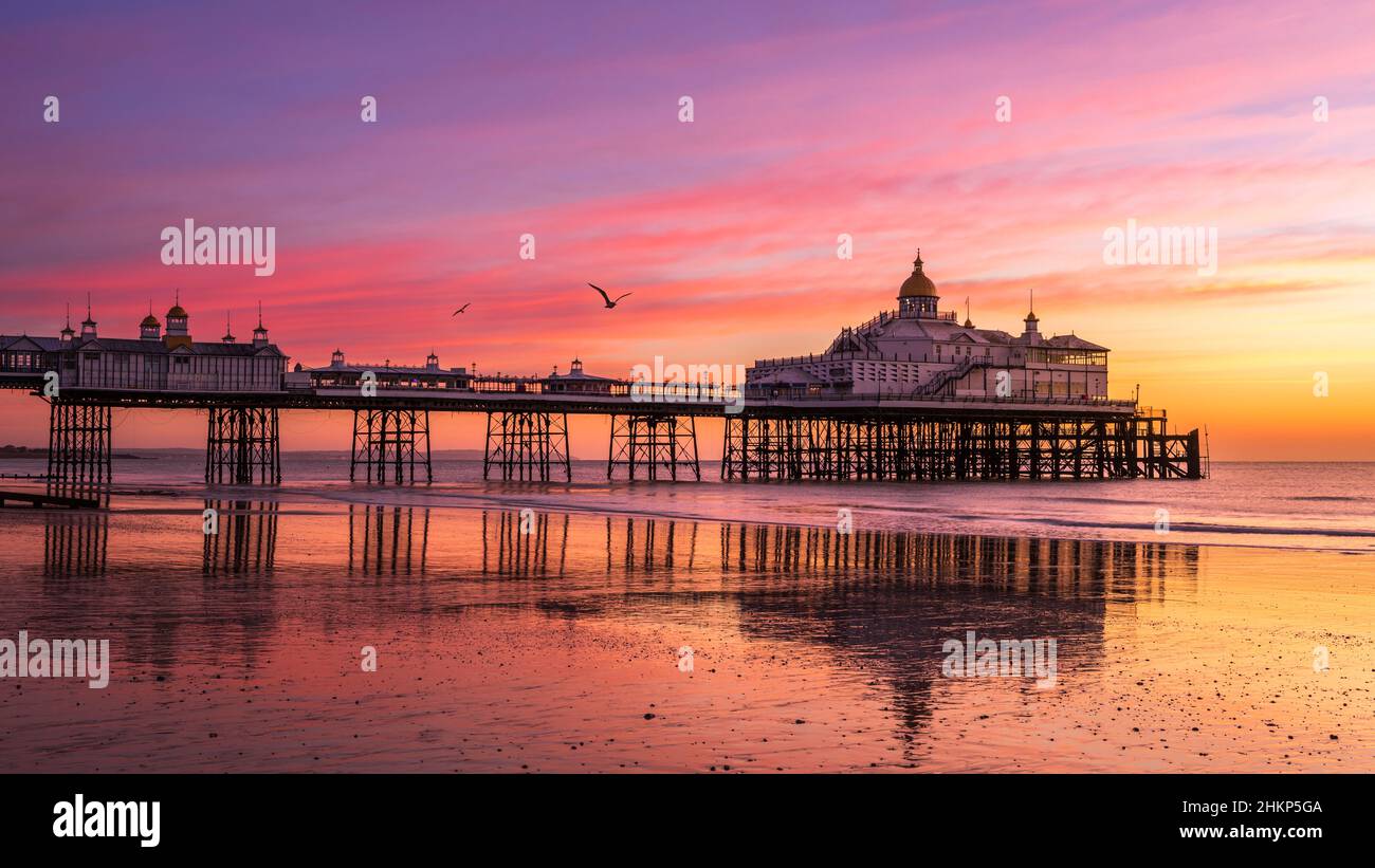 Colourful February sunrise at low tide Eastbourne Pier East Sussex south east England Stock Photo