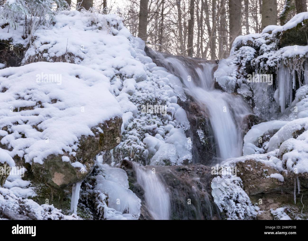 photography with contrasts of frozen and running water, spring water flows over pieces of limestone, running water freezes to form various beautiful s Stock Photo