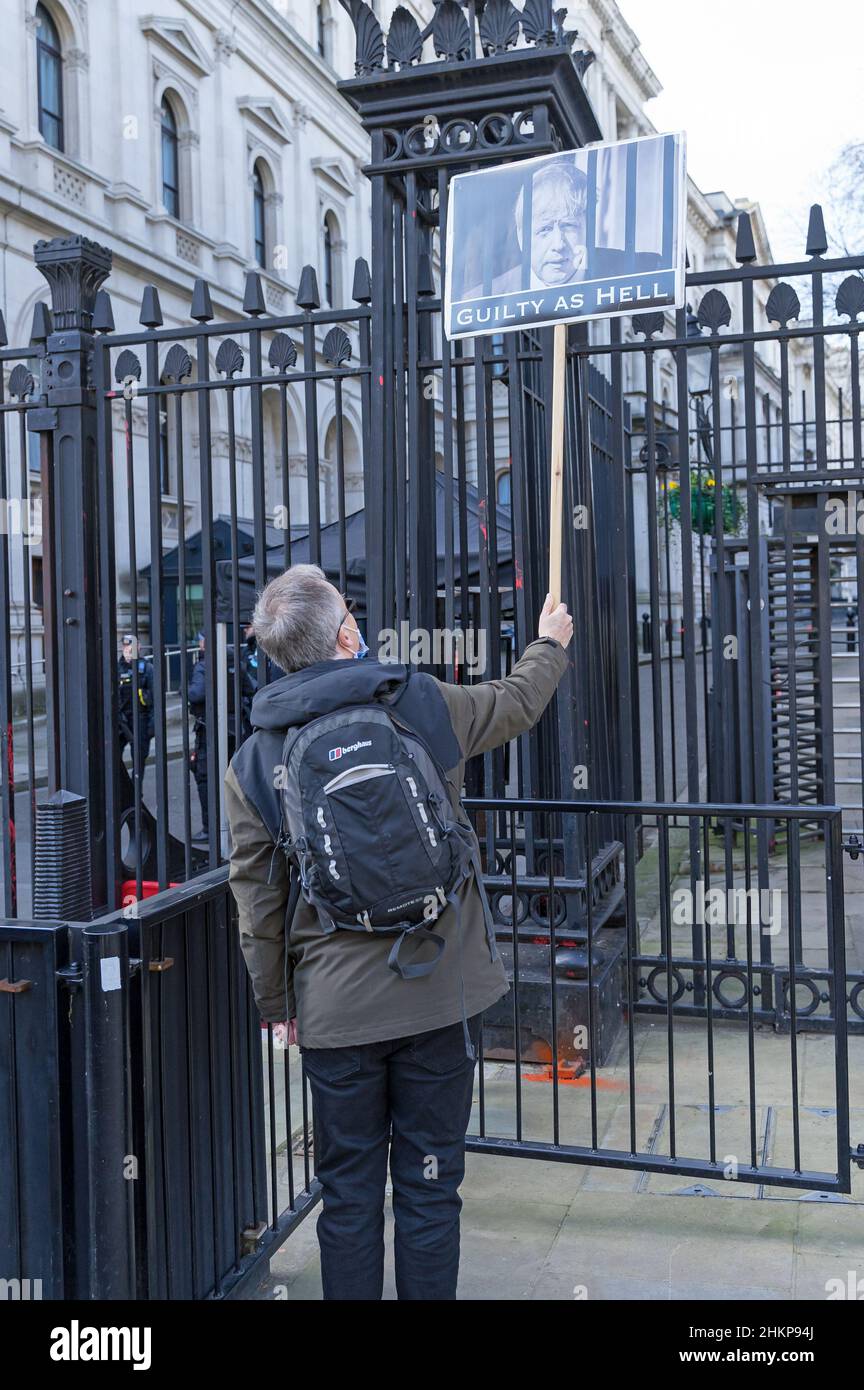 Man protesting alone outside 10 Downing Street holding a placard with a picture of Boris Johnson with the word guilty below. London - 5th Feb 2022 Stock Photo