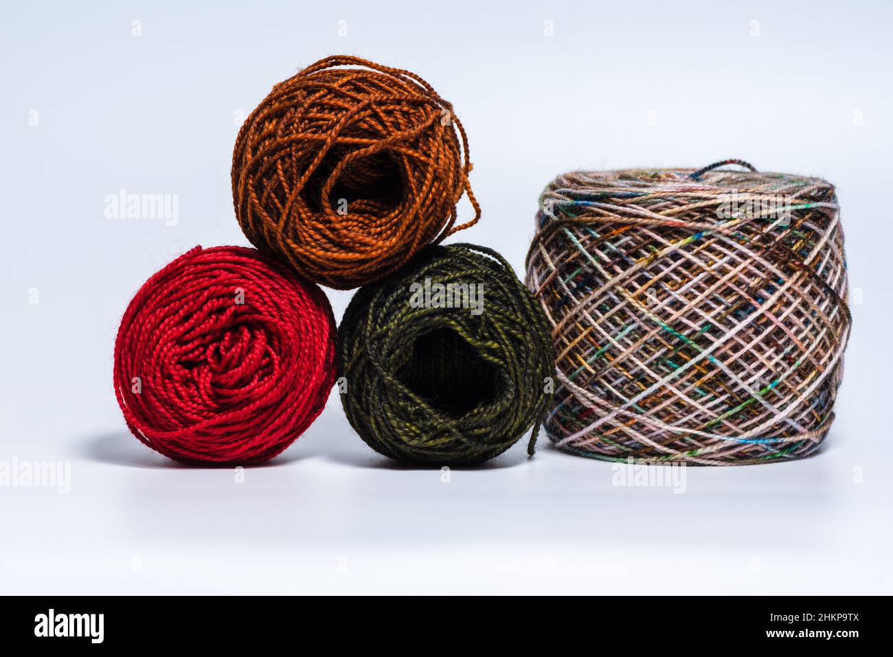 Multiple skeins balls of yarn with loose thread on white background