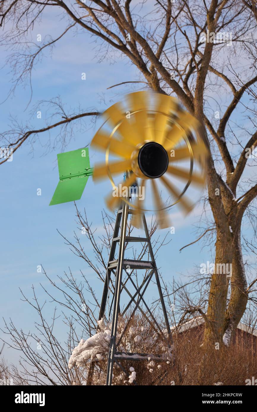 A small Windmill or Wind Turbine in a Rural Setting with Spinning Blades Stock Photo