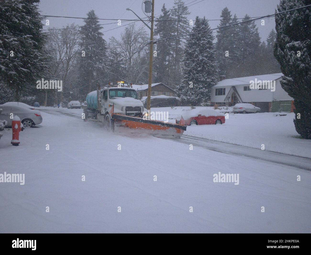 A municipal snow plow clears a snowy street after a heavy snowfall in British Columbia, Canada. Stock Photo