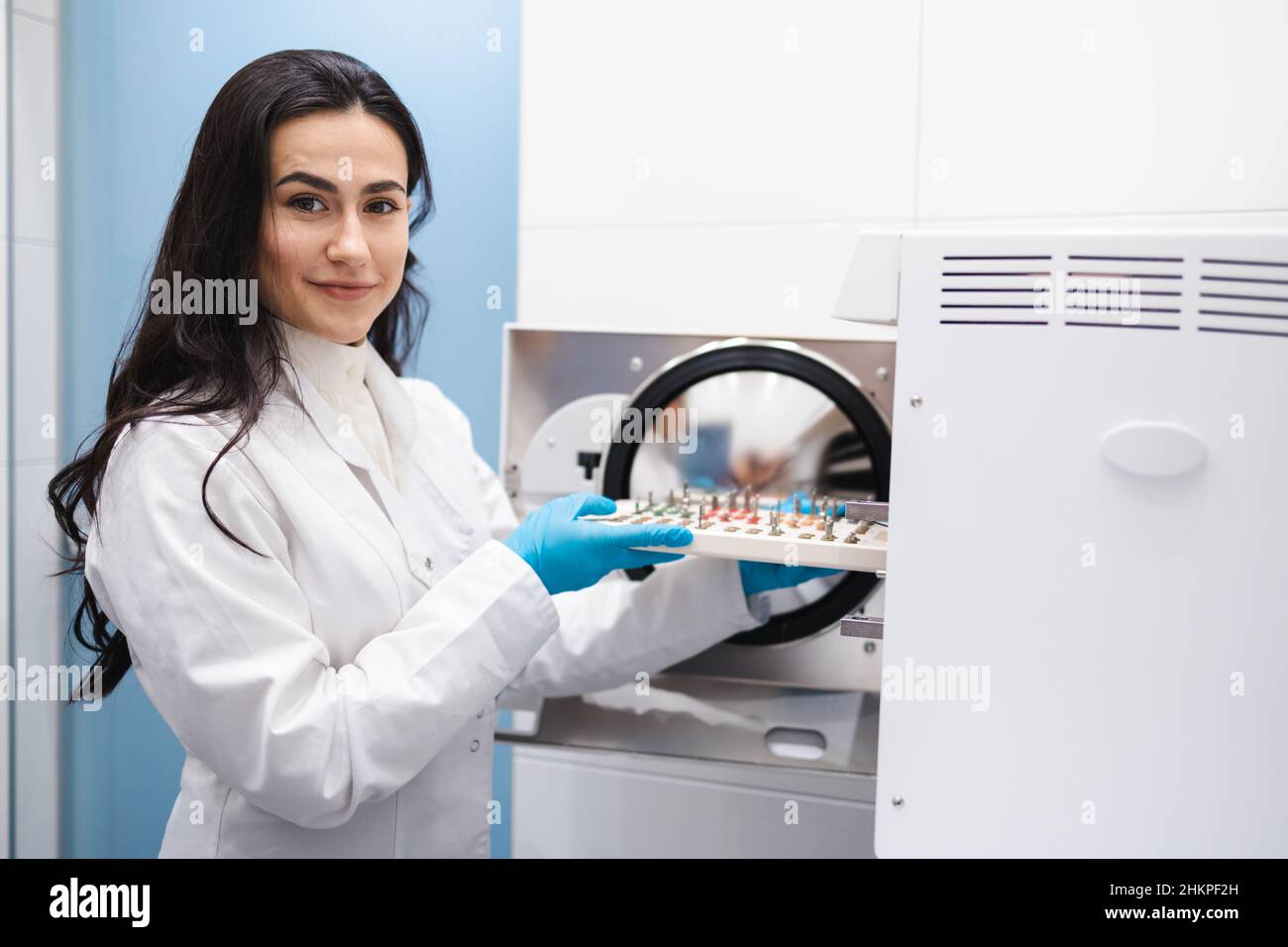 Young female assistant putting dental implant surgery set into