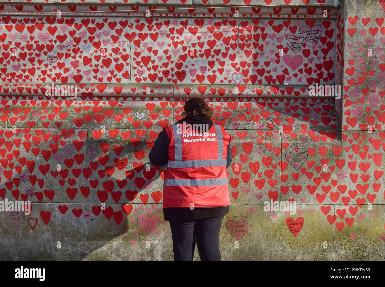 London, UK 4th February 2022. Volunteers paint new hearts and repaint some which have faded over time on the National Covid Memorial Wall. Over 150,000 red hearts have been painted on the wall outside St Thomas' Hospital opposite the Houses of Parliament, one for each life lost to COVID-19 in the UK. Stock Photo