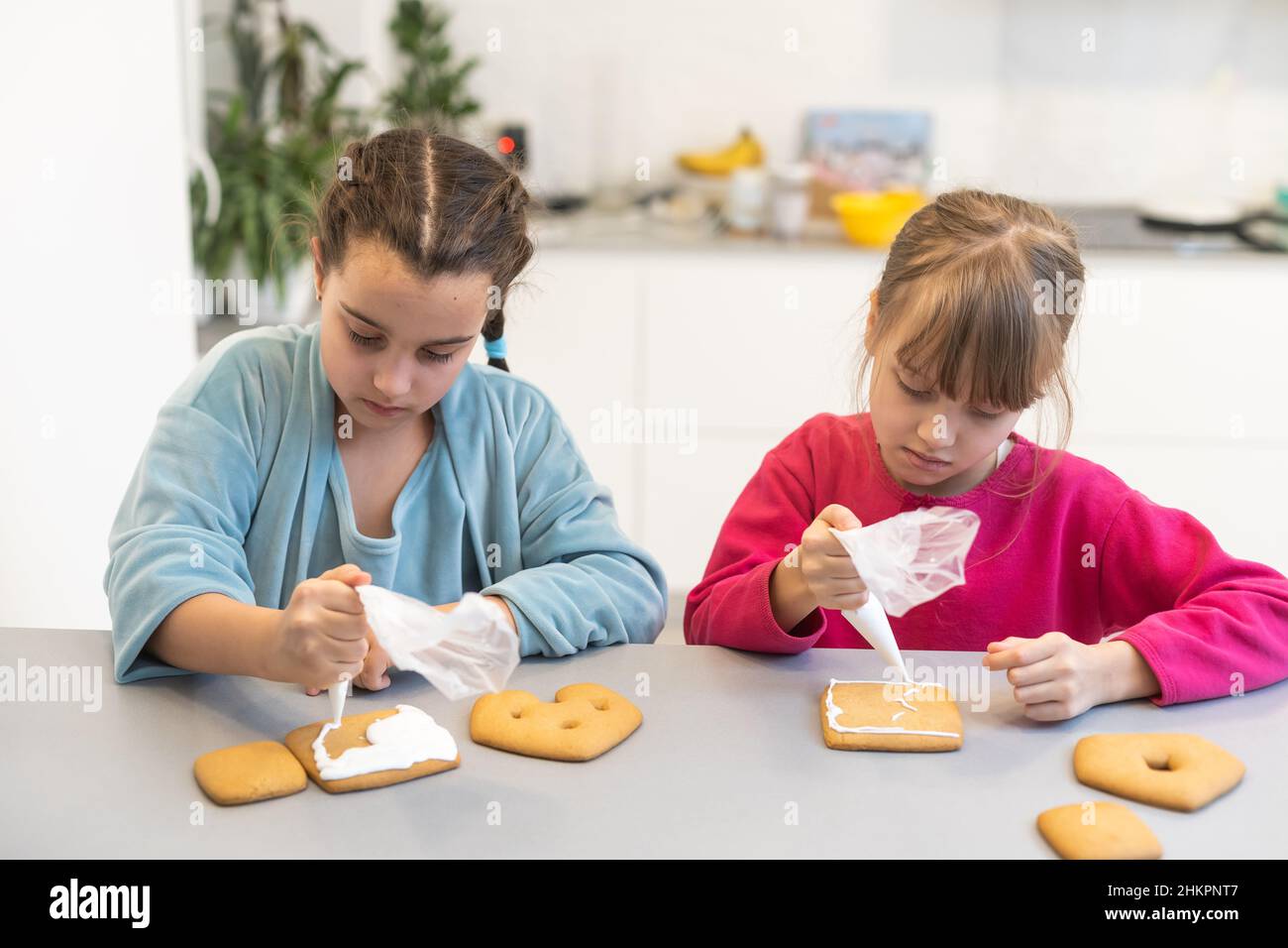 Child Getting Two Cookies Portrait of happy small children decorating homemade cookies in kitchen ...
