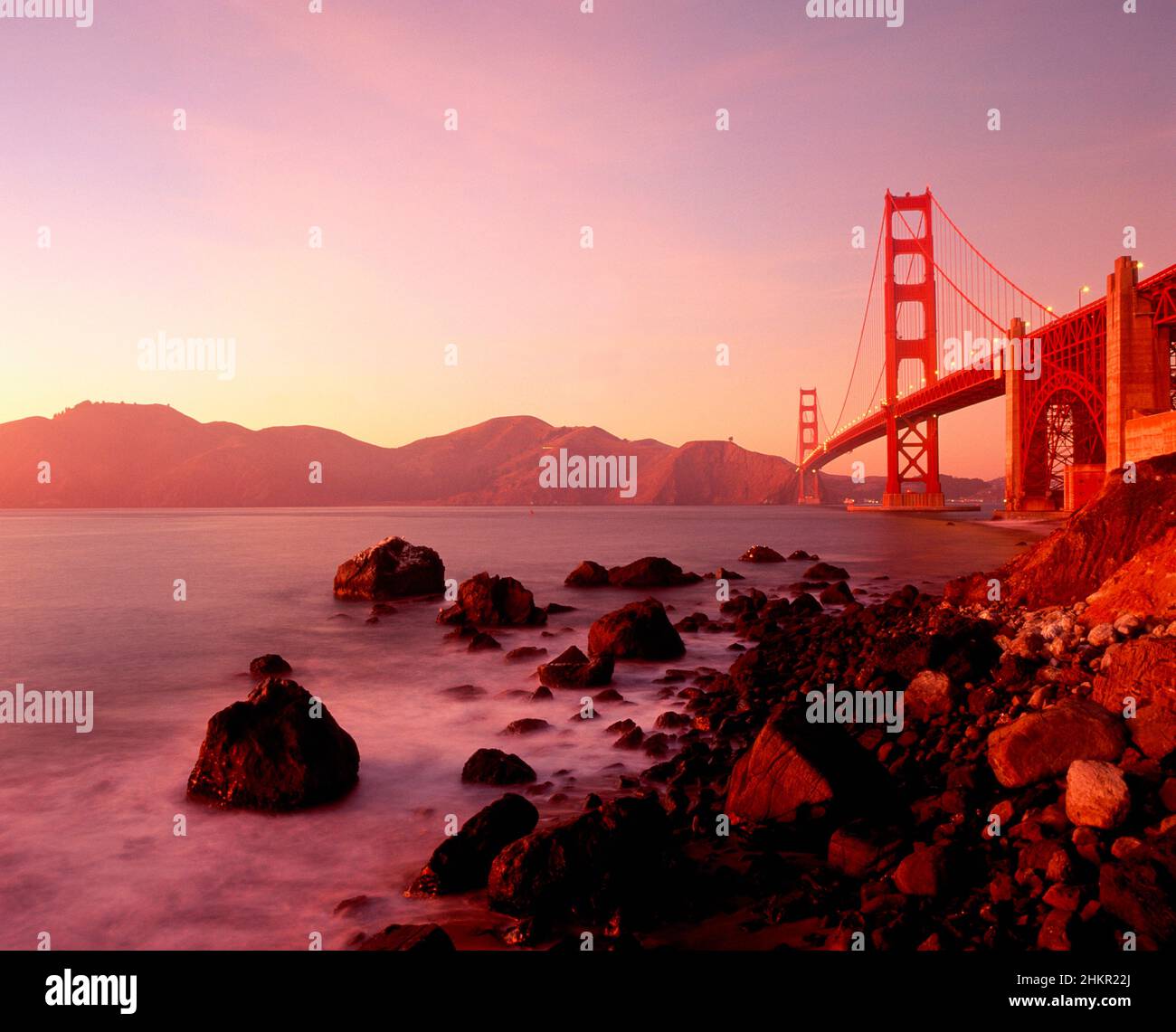 Golden Gate Bridge at sunset with warm light from Baker Beach, San