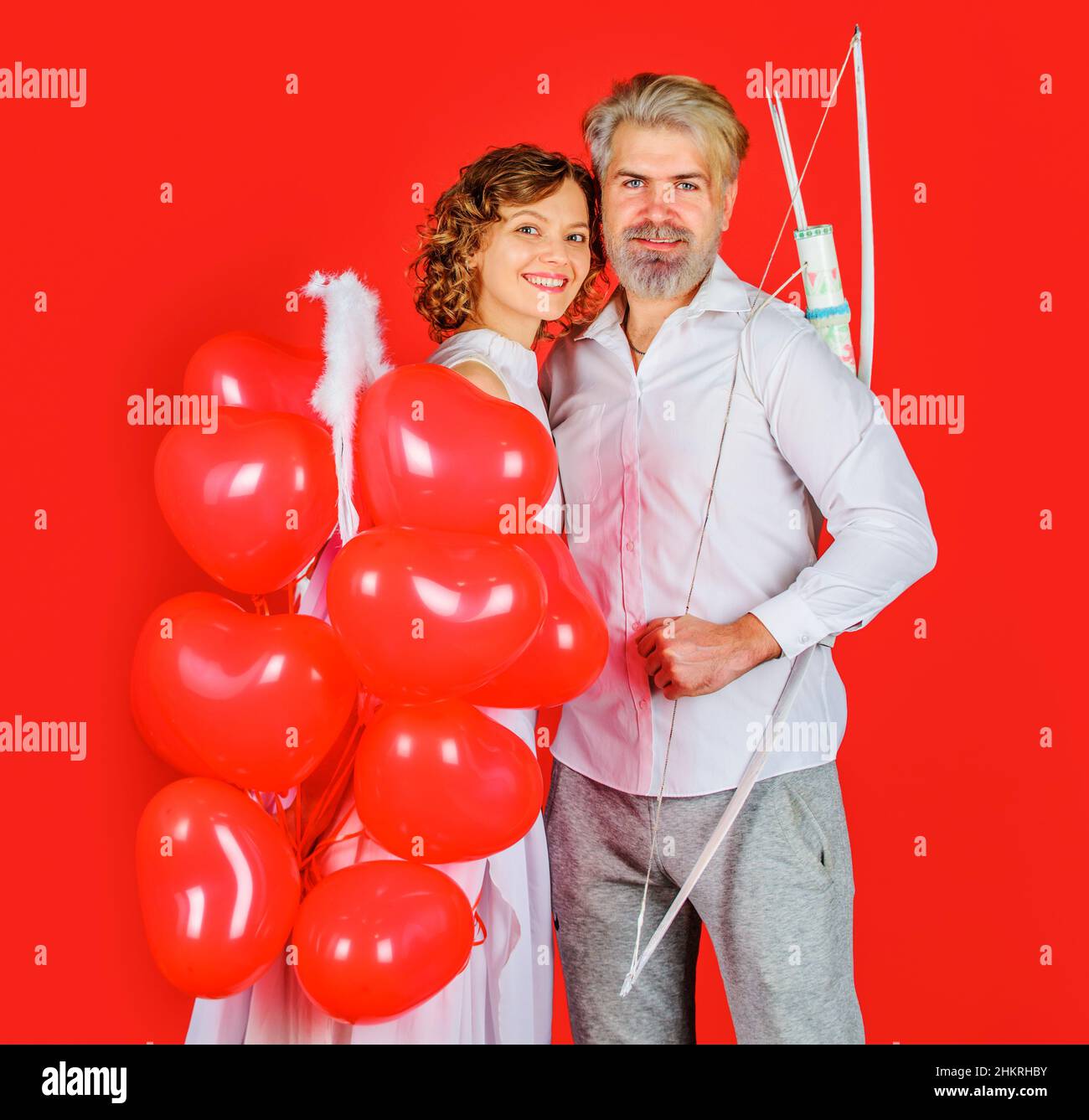 Valentines day couple. Angel with heart shape balloons. Cupid with bow and arrows. Relationships. Stock Photo