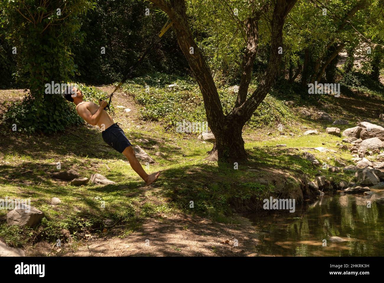 Latin Fit young man is training outdoor on TRX. Copy space Stock Photo