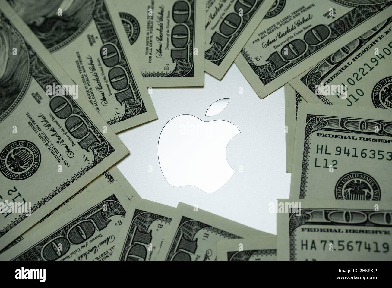 Apple company logo seen on Macbook M1 laptop surrounded by US dollar banknotes. Concept. Selective focus. United Kingdom, Stafford, December 18, 2021. Stock Photo