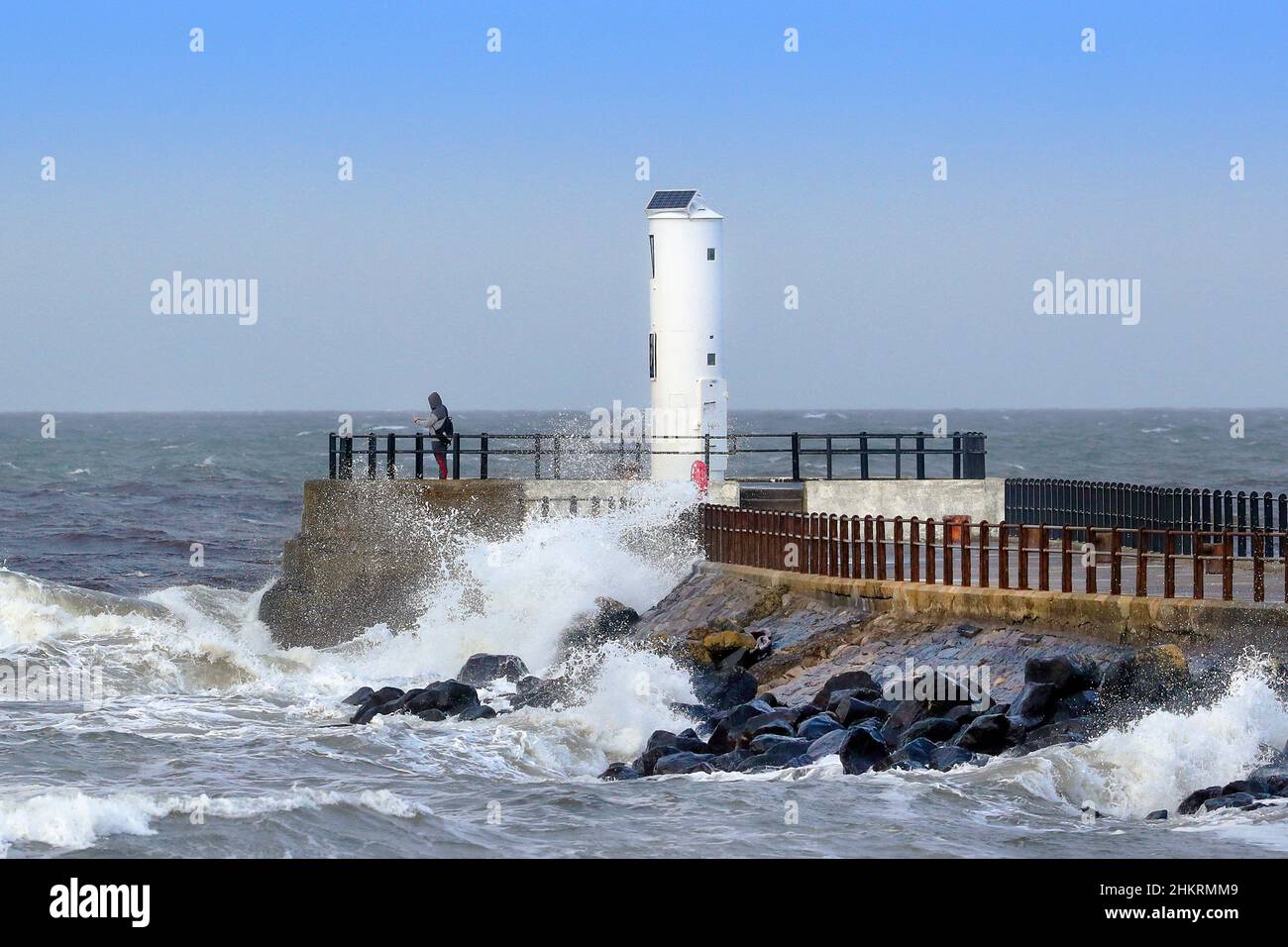 Lighthouse at the end of the pier, Ayr, Ayrshire, Scotland with high waves against the wall from the Firth of Clyde Stock Photo