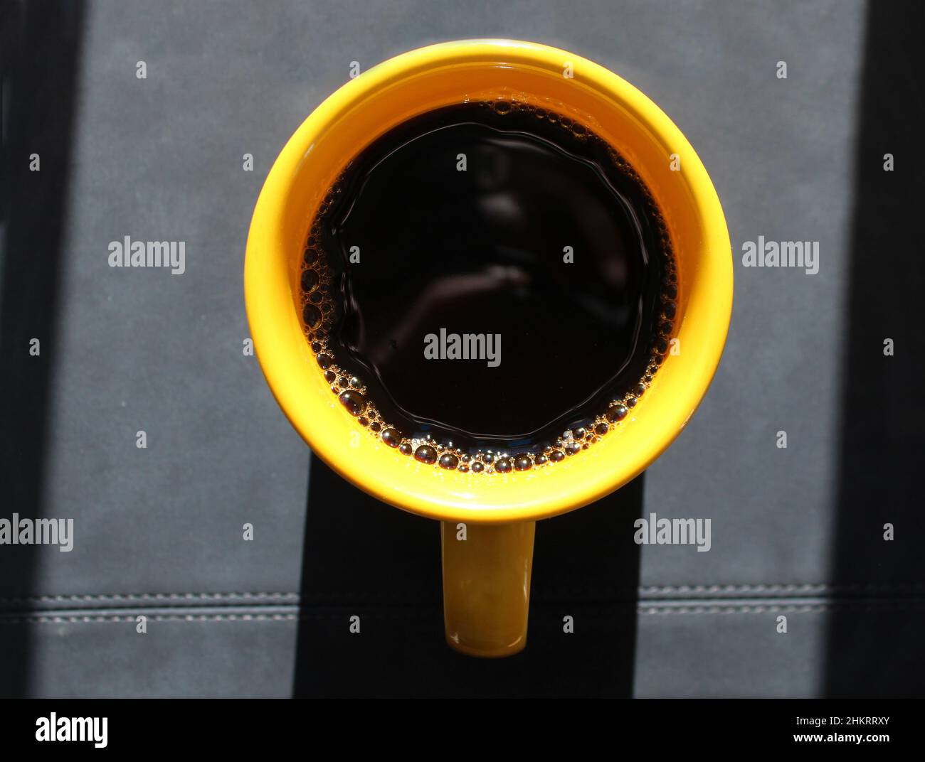 A Bright Yellow Mug Filled with Black Coffee Stock Photo