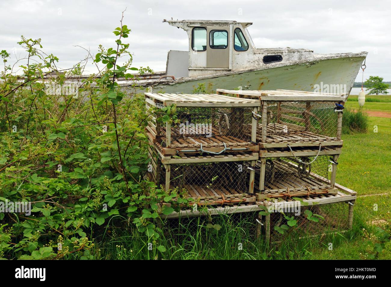 Wooden fishing traps are stacked near a weathered old boat stored on land in the south shore community of Victoria, Prince Edward Island. Stock Photo