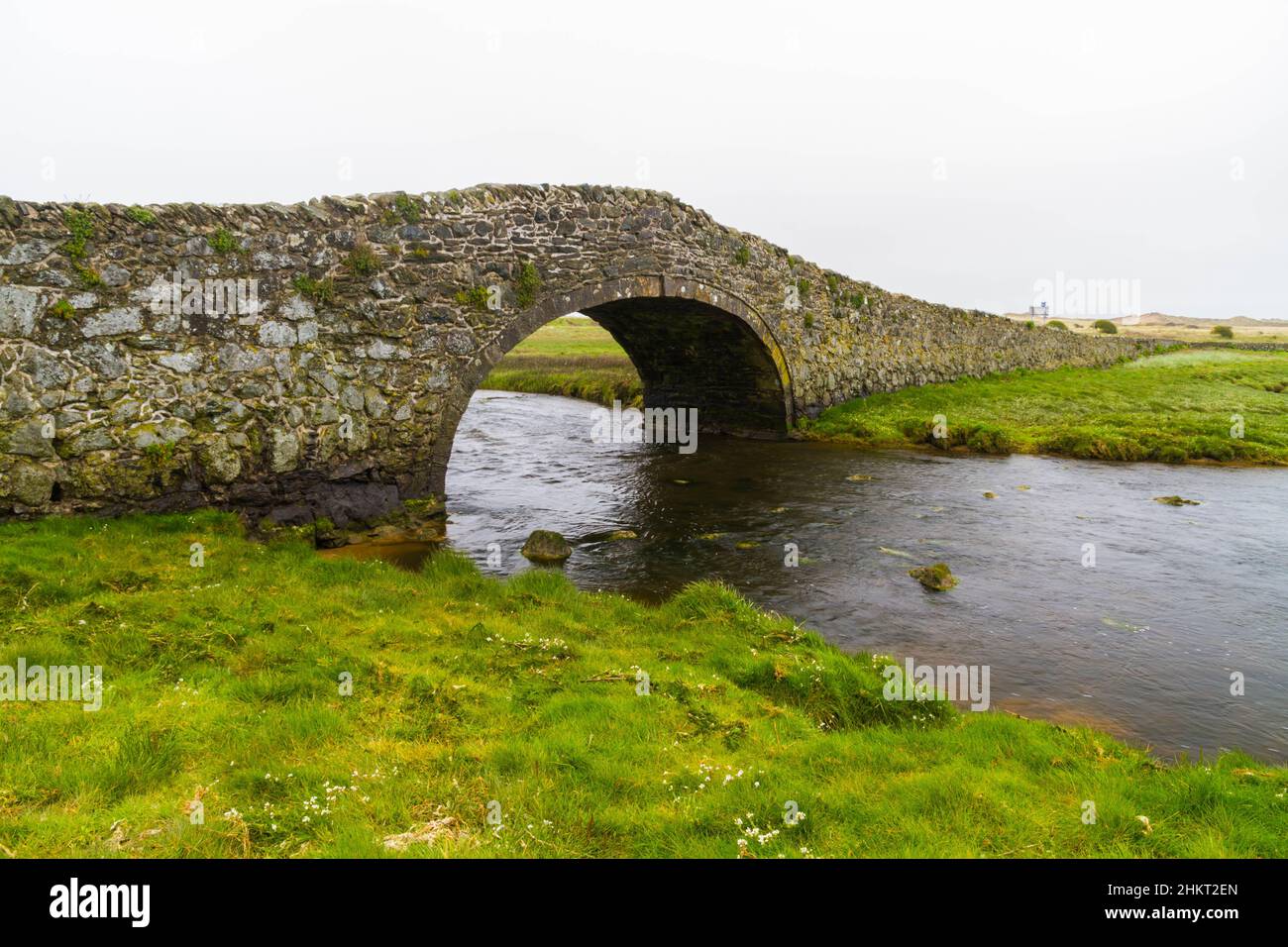 Old hump-backed bridge Pont Pont Aberffraw on Anglesey, Wales UK, landscape Stock Photo