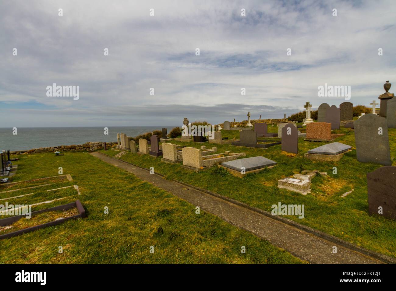 Back of gravestones on clifftop cemetery, sea in background Stock Photo