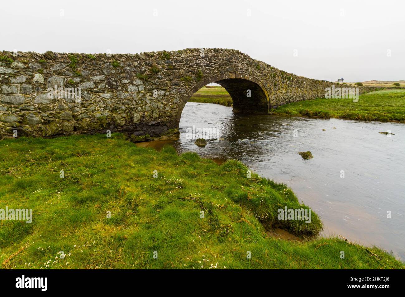 Old hump-backed bridge Pont Pont Aberffraw on Anglesey, Wales UK, wide angle, landscape Stock Photo
