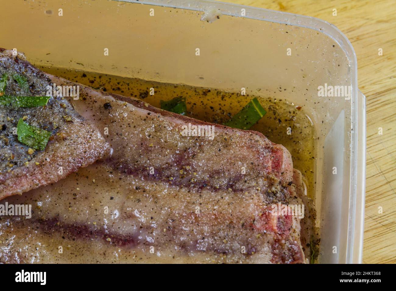 Dry salt cure on Pork belly joint in dry salt cure  becoming streaky bacon with liquid brine drawn from the meat, close up Stock Photo